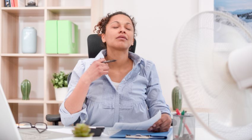 woman with hyperthyroidism sitting in front of a fan to cool off